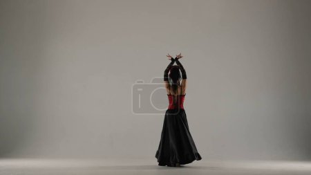 Téléchargez les photos : Chorégraphie moderne une danse. Femme danseuse dansant sur fond blanc. Femme en robe de style flamenco effectue des mouvements élégants de danse espagnole avec ses mains et son corps dans le studio. - en image libre de droit