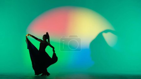 Photo for Modern choreography an dance. Woman silhouette dancing on colorful background. Graceful dancer passionately dancing flamenco performing elements of Spanish style choreography. - Royalty Free Image