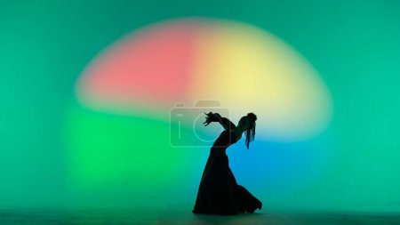 Photo for Modern choreography an dance. Woman silhouette dancing on colorful background. Graceful dancer passionately dancing flamenco performing elements of Spanish style choreography. - Royalty Free Image