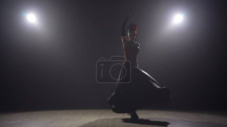 Téléchargez les photos : Chorégraphie moderne une danse. Femme dansant sur fond noir sous les projecteurs. Danseuse espagnole en robe rouge-noire éléments de danse de flamenco passionné. - en image libre de droit
