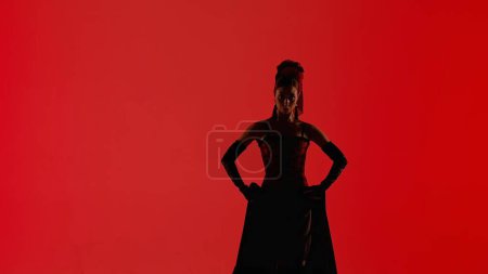 Moderne Choreographie und Tanz. Tänzerin tanzt auf rotem Hintergrund. Frau im Flamenco-Kleid führt elegante spanische Tanzbewegungen mit Händen und Körper im Studio aus.
