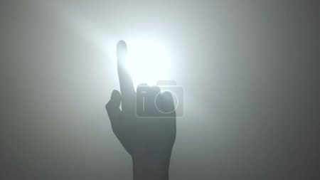 Photo for Silhouette in lighting concept. Female model against bright backlight on black smoky background in studio. Female silhouette with a moving hand playing with a beam of light in the dark. Close up - Royalty Free Image