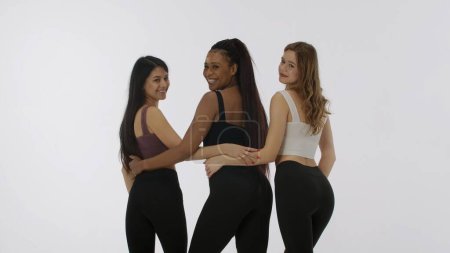 Foto de Retrato de jóvenes modelos multiétnicos sobre fondo de estudio blanco de cerca. Grupo de tres atractivas chicas multirraciales abrazar y sonreír a la cámara concepto de belleza multiétnica - Imagen libre de derechos