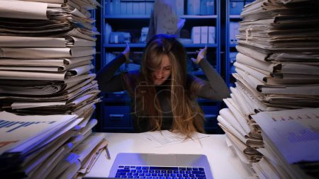 Photo for Hard work concept. Exhausted young business woman office employee at the desk working late at night overloaded with paperwork. The woman is very upset and angry. - Royalty Free Image