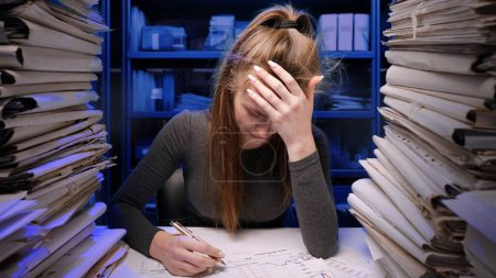 Photo for Hard work concept. Exhausted young business woman office employee at the desk working late at night overloaded with paperwork. Female reads documents stressed, angry, depressed expression. - Royalty Free Image