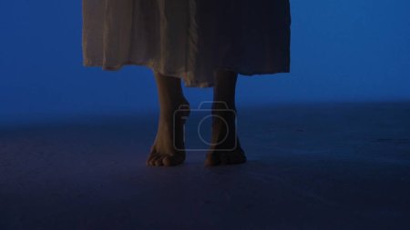 Photo for Contemporary experimental choreography concept. Female dancer performing in the studio. Young woman in dark studio dancing barefoot on the floor, feet close up. - Royalty Free Image