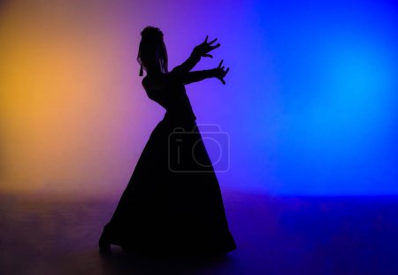 Téléchargez les photos : Chorégraphie moderne une danse. Silhouette femme dansant sur fond coloré. Danseuse gracieuse dansant passionnément des éléments de chorégraphie flamenco de style espagnol. - en image libre de droit