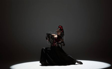 Téléchargez les photos : Chorégraphie moderne une danse. Femme dansant sur fond noir sous les projecteurs. Danseuse espagnole en robe rouge-noire éléments de danse de flamenco passionné. - en image libre de droit
