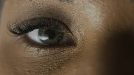 Foto de Tratamiento de la vista concepto de servicios oftalmológicos. Macro de cara de modelo femenino. mujer afroamericana disparo cara recortada, ojos verdes mirando a la cámara. - Imagen libre de derechos
