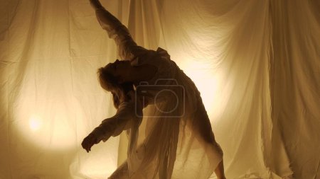 Foto de Silhouette concepto de coreografía experimental contemporánea. Bailarina actuando en el estudio. Chica joven bailando contra la luz de fondo caliente. - Imagen libre de derechos