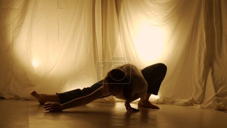 Foto de Silhouette concepto de coreografía experimental contemporánea. Bailarina actuando en el estudio. Chica joven bailando contra la luz de fondo caliente. - Imagen libre de derechos