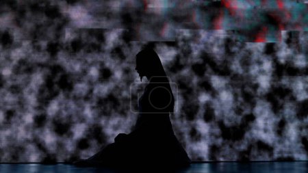 Photo for Halloween horror movie creative concept. Silhouette against digital television screen. Thriller scene scared woman silhouette sitting on the floor and praying against big digital screen with noise. - Royalty Free Image