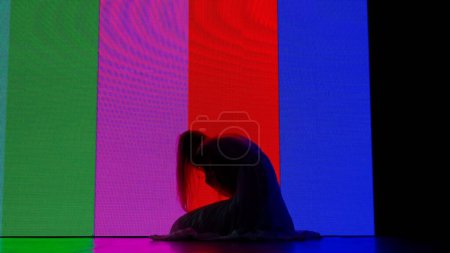 Photo for Halloween horror movie creative concept. Silhouette against digital television screen. Thriller scene woman silhouette sitting on the floor crawling up on big digital screen. - Royalty Free Image