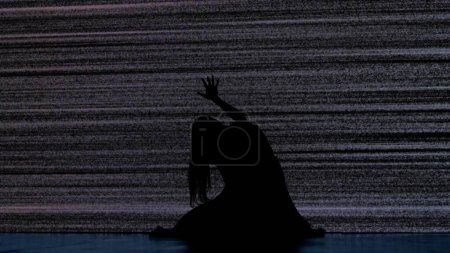 Photo for Halloween horror movie creative concept. Silhouette against digital television screen. Thriller scene scared trapped woman silhouette sitting on the floor hitting big digital screen with noise. - Royalty Free Image