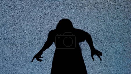 Photo for Halloween horror movie creative concept. Silhouette against digital television screen. Thriller scene spooky woman crawls walks back in front of big digital screen with white noise. - Royalty Free Image