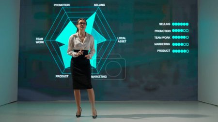Photo for A professional businesswoman is giving a presentation in a modern setting, with a data visualization screen behind her. The screen shows various business-related terms - Royalty Free Image