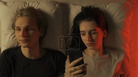 Photo for Love intimate relationships concept. Top view loving couple romantic time in bedroom. Man and woman sensual lovers smiling talking laying in bed together, female with smartphone, intimacy and bonding. - Royalty Free Image