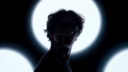 Téléchargez les photos : Concept de technologie visuelle numérique. Homme en lunettes contre mur numérique noir. Silhouette homme gros plan debout devant le mur d'écran numérique avec des symboles abstraits dans le club sombre. - en image libre de droit