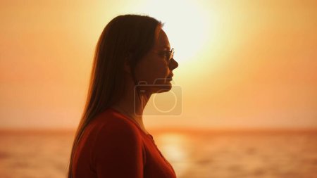 Photo for The image captures the profile of a thoughtful woman silhouetted against the captivating glow of the setting sun, evoking a sense of introspection and the beauty of dusk - Royalty Free Image