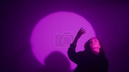 Photo for Girl channeling her inner rhythm through hip hop dance, illuminated by the radiant hues of a colorful spotlight. Watch as every dynamic move and bold step reflects the vibrant beat of urban expression - Royalty Free Image