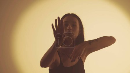 Photo for Girl dancing hip-hop on the background of bright yellow projector. Every move resonates with the heart of street dance, syncing perfectly with the vibrant ambiance. - Royalty Free Image