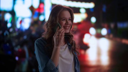 Photo for Gadgets and modern everyday life advertisement concept. Female using smartphone on daily basis. Young woman in the city downtown at night talking on smartphone. - Royalty Free Image