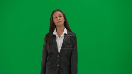 Téléchargez les photos : Reportage TV et concept de publicité de diffusion en direct. Rapporteuse isolée sur fond vert chroma key. Femme afro-américaine présentatrice de nouvelles hôte en costume regardant autour. - en image libre de droit