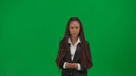 Téléchargez les photos : Reportage TV et concept de publicité de diffusion en direct. Rapporteuse isolée sur fond vert chroma key. Femme afro-américaine présentatrice en costume regardant la caméra. - en image libre de droit