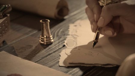 Photo for Historical letter creative concept. Female in antique outfit writes with feather pen. Close up shot of woman writing a letter with vintage quill feather pen on old parchment paper at the desk. - Royalty Free Image