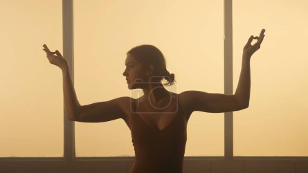 Téléchargez les photos : La jeune danseuse exprime une profonde émotion à travers sa danse contemporaine. Sa silhouette, soulignée par un éclairage doux, reflète la fluidité délicate et la grâce de ses mouvements. - en image libre de droit