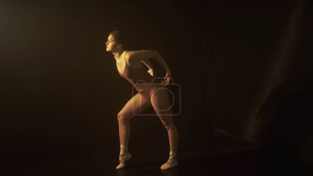 Foto de Esencia de la danza a través de la delicada interacción de la luz y la sombra, como un bailarín se mueve con equilibrio. La iluminación sutil subraya la fluidez y la gracia del movimiento de los bailarines. - Imagen libre de derechos