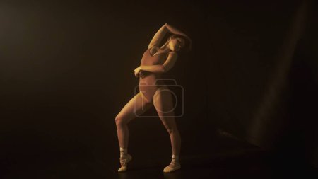 Photo for Essence of dance through the delicate interplay of light and shadow, as a dancer moves with poise. The subtle lighting underscores the fluidity and grace of the dancers motion. - Royalty Free Image
