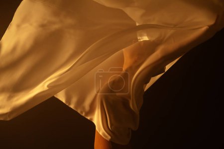 Essence of dance through the delicate interplay of light and shadow, as a dancer shrouded in white chiffon moves with poise. The subtle lighting underscores the fluidity and grace of dancers motion