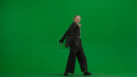 Photo for Woman in black business suit dancing cheerfully on green screen with chromakey. Modern businesswoman creative advertising concept. - Royalty Free Image
