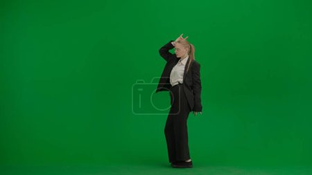 Photo for Woman in black business suit dancing cheerfully on green screen with chromakey. Modern businesswoman creative advertising concept. - Royalty Free Image