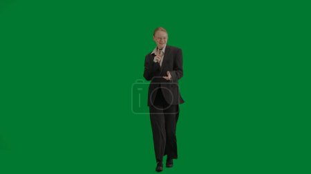 Woman in black business suit dancing cheerfully on green screen with chromakey. Modern businesswoman creative advertising concept.