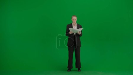 Modern businesswoman creative advertisement concept. Portrait of female in suit on chroma key green screen. Blonde business woman in formal outfit holding paper.