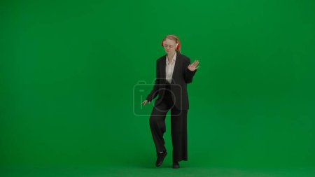 Woman in black business suit dancing cheerfully on green screen with chromakey. Modern businesswoman creative advertising concept.