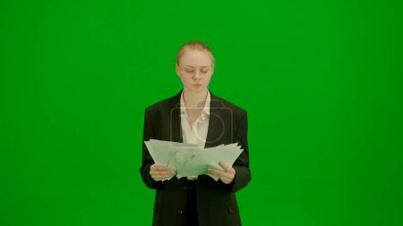 Modern businesswoman creative advertisement concept. Portrait of female in suit on chroma key green screen. Blonde business woman in formal outfit holding paper.