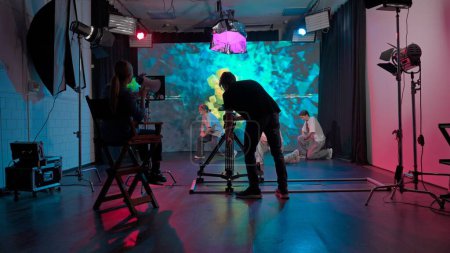 Backstage-Videodreh, bei dem der Kameramann filmt und der Regisseur das Trio der Tänzer kontrolliert, die im Hip-Hop-Straßenstil tanzen. Zwei Mädchen und ein Mann tanzen gegen einen großen LED-Bildschirm.