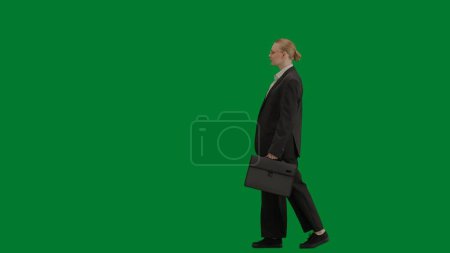 Téléchargez les photos : Concept moderne de publicité créative femme d'affaires. Portrait de femme en costume sur écran vert chromé. Femme d'affaires blonde en tenue formelle marchant avec mallette. Vue latérale. - en image libre de droit
