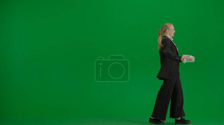 Téléchargez les photos : Concept moderne de publicité créative femme d'affaires. Femmes en costume d'affaires sur écran vert avec clé chromatique. Femme d'affaires blonde avec de l'argent dans les mains. - en image libre de droit