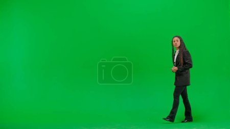 Tv news and live broadcasting concept. Young female reporter isolated on chroma key green screen background. Full shot african american woman tv news host talking with serious face.