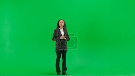 Tv news and live broadcasting concept. Young female reporter isolated on chroma key green screen background. Full shot african american woman tv news host anchor talking looking at camera.