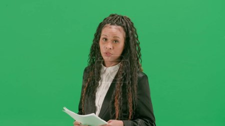 Photo for Tv news and live broadcasting concept. Young female reporter isolated on chroma key green screen background. African american woman tv news host sit in chair with tablet taking interview. - Royalty Free Image