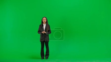 Tv news and live broadcasting concept. Young female reporter isolated on chroma key green screen background. Full shot african american woman tv news host talking with serious face.