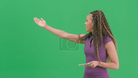 Tv news and live broadcasting concept. Female in dress isolated on chroma key green screen background. African american woman tv news host standing talking looking at camera.