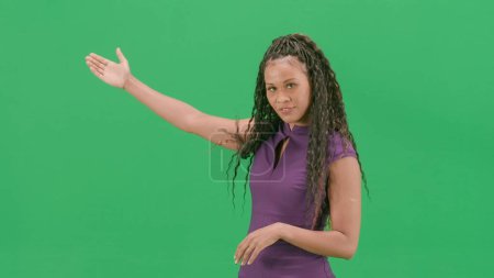 Tv news and live broadcasting concept. Female in dress isolated on chroma key green screen background. African american woman tv news host standing talking looking at camera.