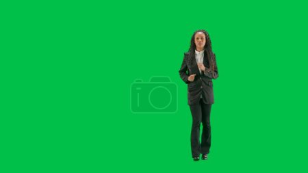 Tv news and live broadcasting concept. Young female reporter isolated on chroma key green screen background. Full shot african american woman tv news host running.