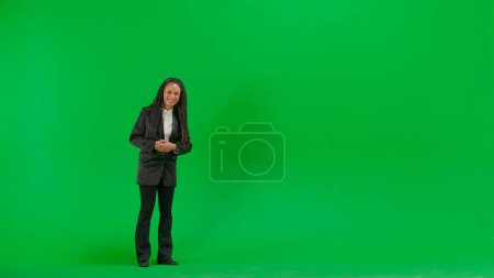 Tv news and live broadcasting concept. Young female reporter isolated on chroma key green screen background. Full shot african american woman tv news host talking smiling at camera.